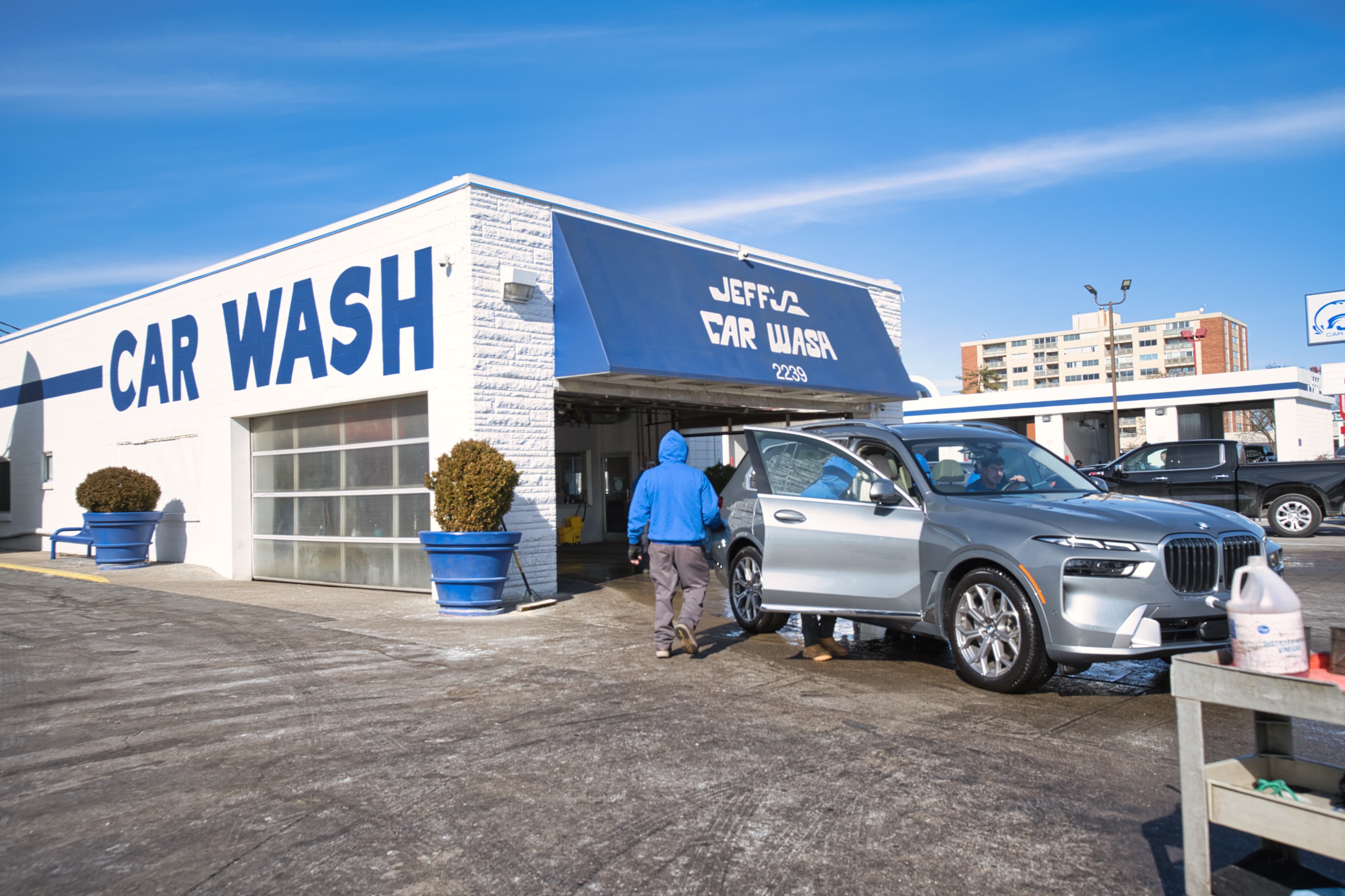 The full-service bay at Jeff's Car Wash on Nicholasville Road — a crew member hand-drying a freshly washed silver SUV under the blue Jeff's Car Wash awning